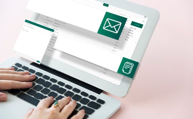 email marketing concept: two hands using a laptop with email and file icons on the screen
