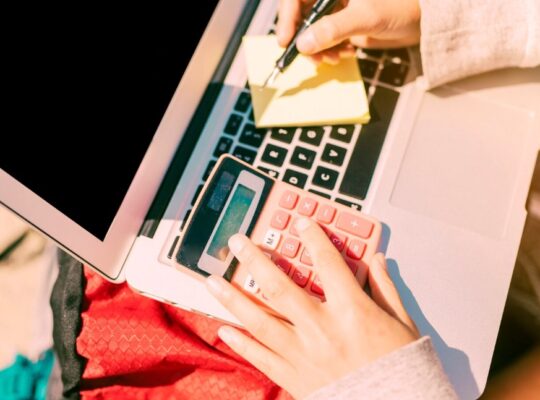 a woman taking notes by hand on a laptop on a sunny day