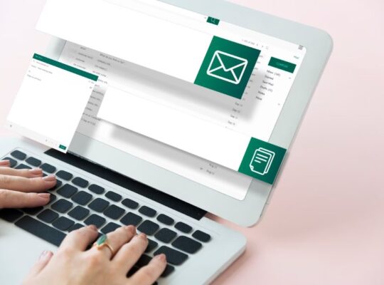 email marketing concept: two hands using a laptop with email and file icons on the screen