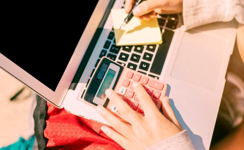 a woman taking notes by hand on a laptop on a sunny day