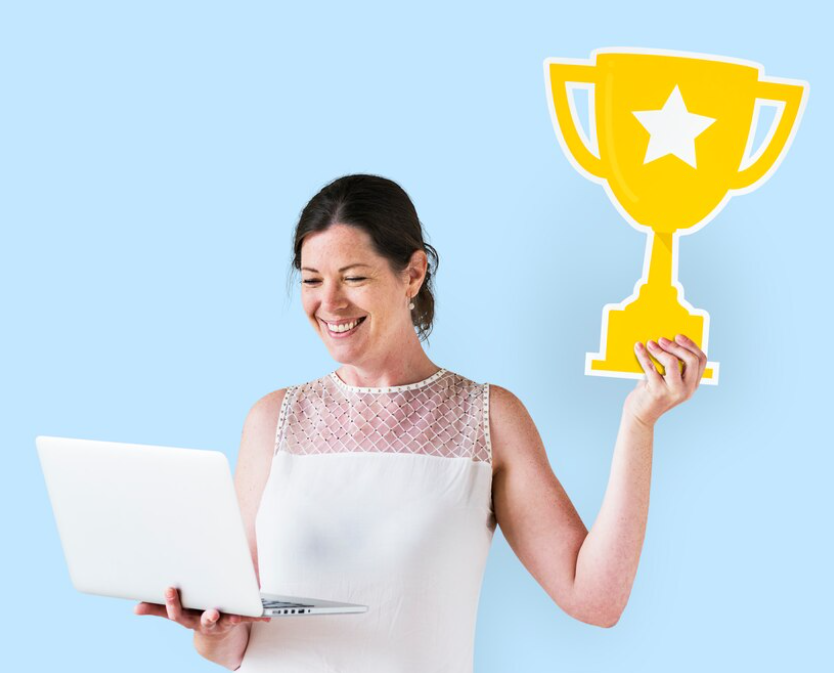 A woman holding a laptop and a trophy, symbolizing success