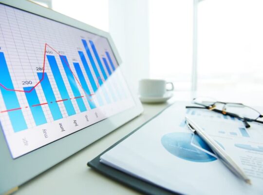 Close-up of a financial bar chart on a tablet with a pen and glasses