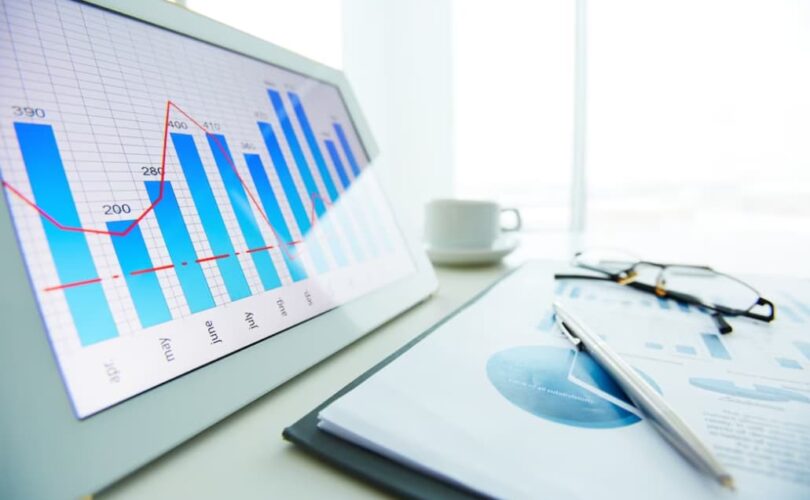 Close-up of a financial bar chart on a tablet with a pen and glasses